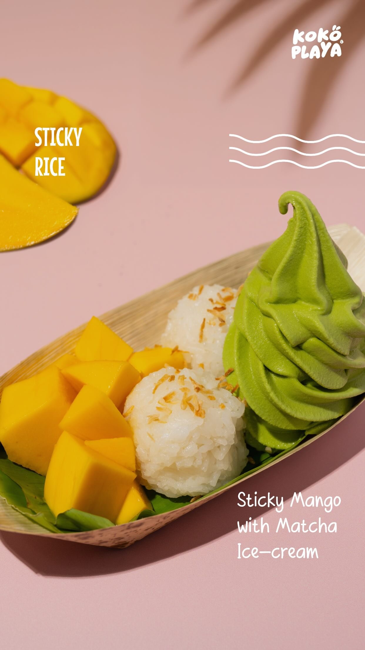 A bamboo boat holding matcha soft serve, two balls of coconut sticky rice and fresh mango cubes, on a pink ground.